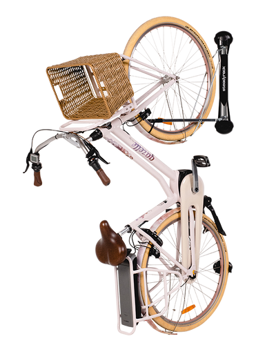 A light pink electric bike with fenders and straw basket hanging vertically on a Steadyrack vertical e-bike rack