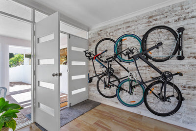 Three bikes stored inside by the front door on pivoting bike racks
