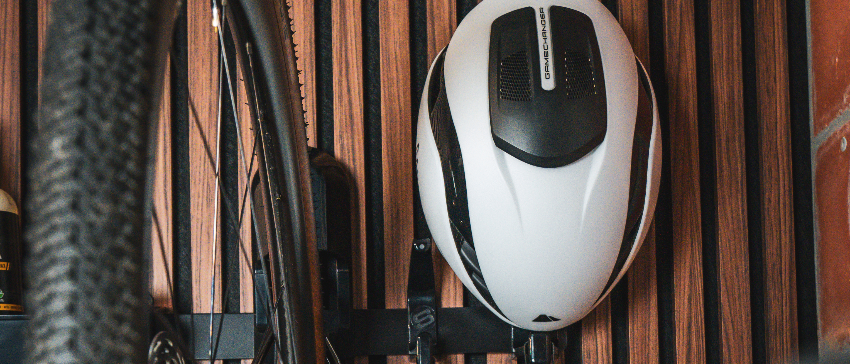 White and black helmet with a bicycle tire on a wooden surface