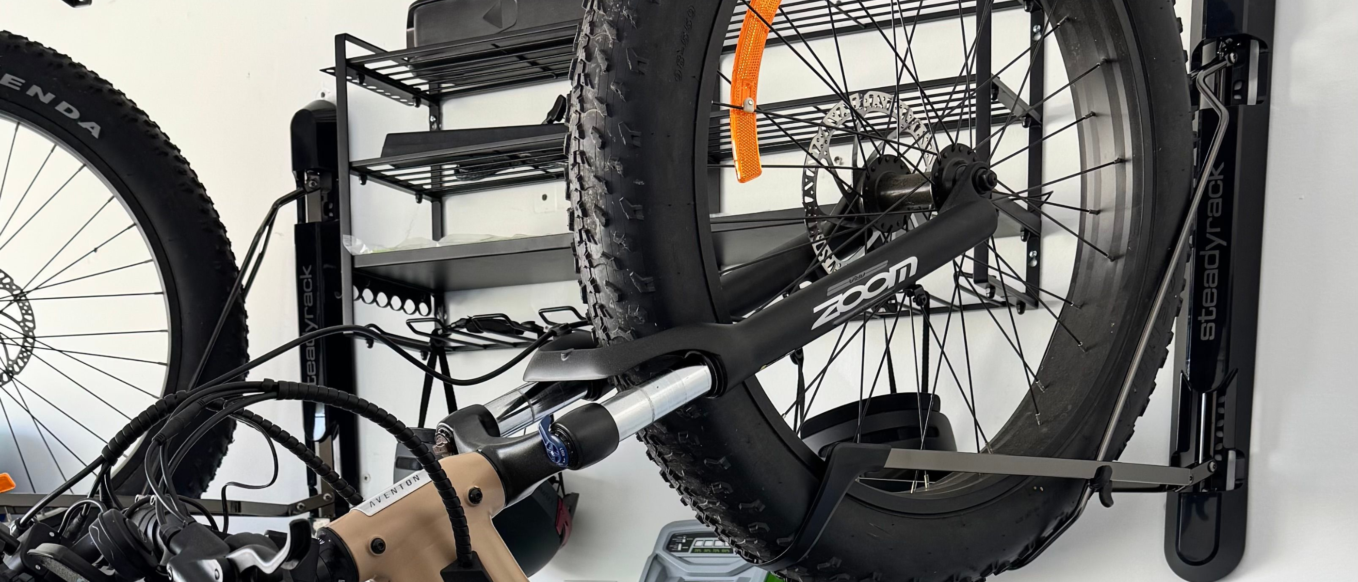 Fat tyre bike mounted on a wall with black metal macking behind. 