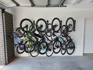 Eight bikes stored on wall mounted bike racks in a garage.