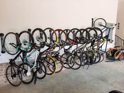 Eleven bikes stored outside a building arranged side by side on wall-mounted bike racks