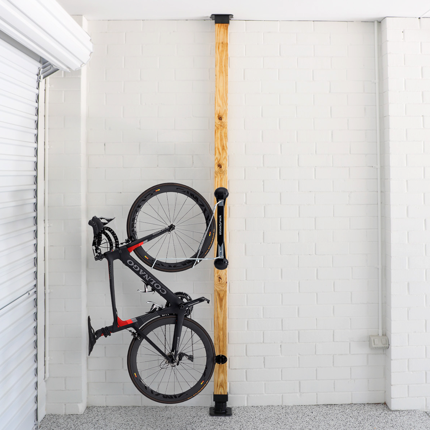 Bicycle installed on a wooden post against a white brick wall.