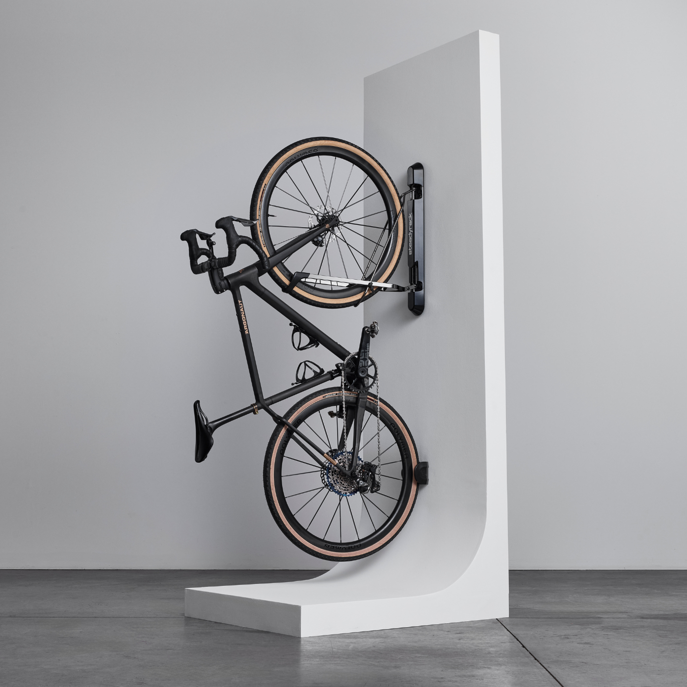 A road bike stored vertically in a bike rack on a white stand