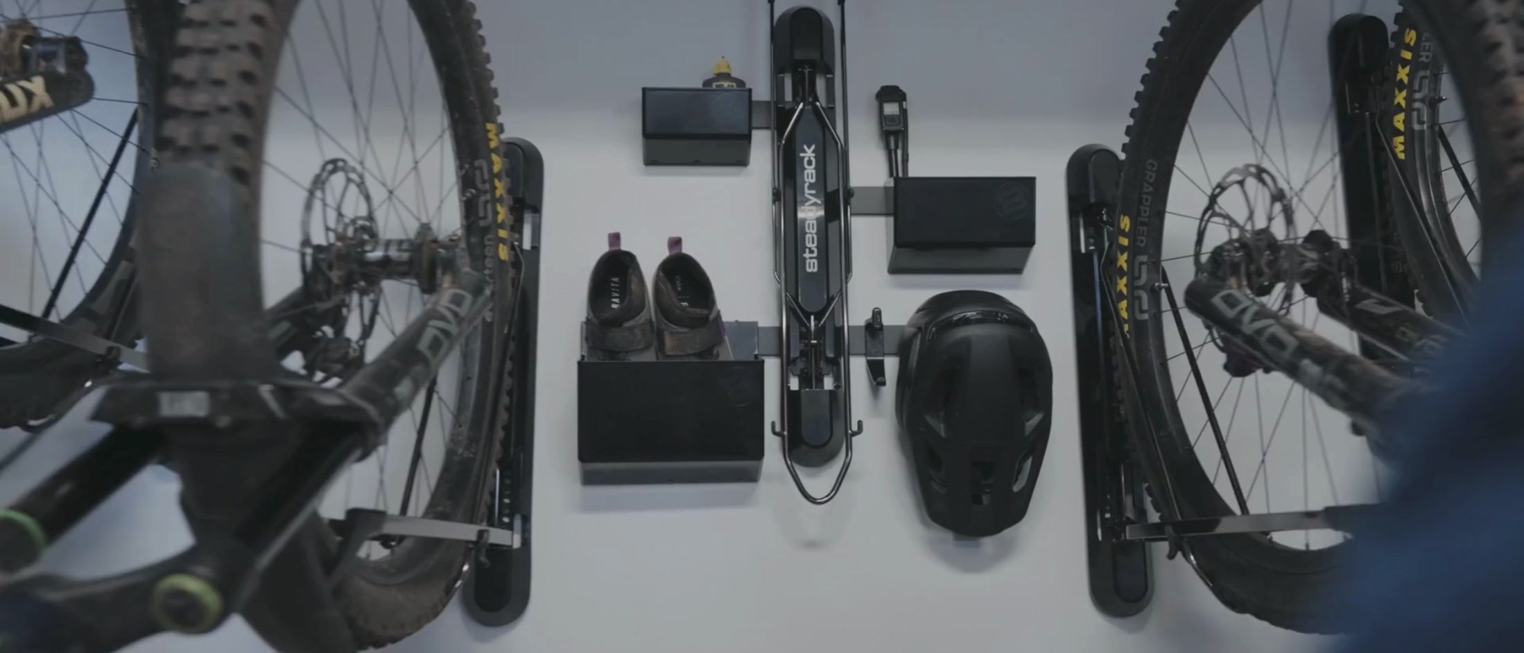 A person taking their helmet off a hook attached to a bike rack. 