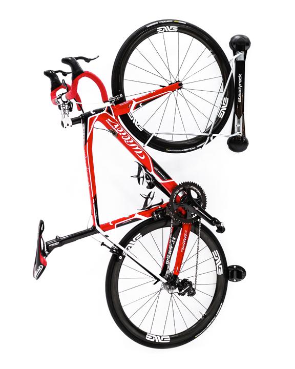 A red road bike hanging vertically on a wall mounted Steadyrack classic bike rack.