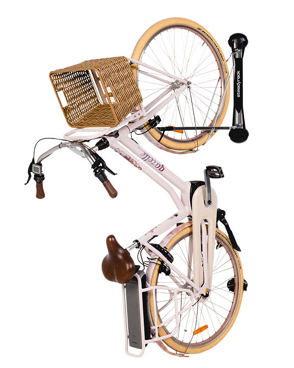 A light pink electric bike with fenders and straw basket hanging vertically on a Steadyrack vertical e-bike rack
