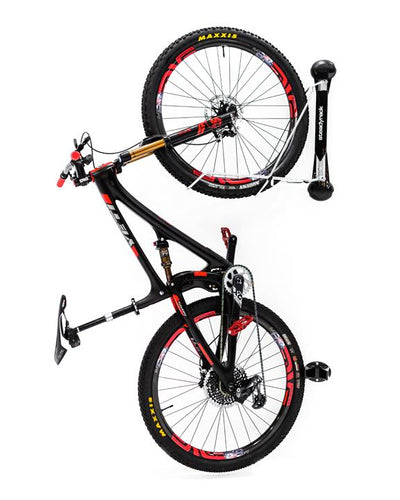 A black and red mountain bike hanging vertically on a wall mounted Steadyrack mountain bike rack.